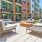 a patio with chairs and tables and a pool in front of a building